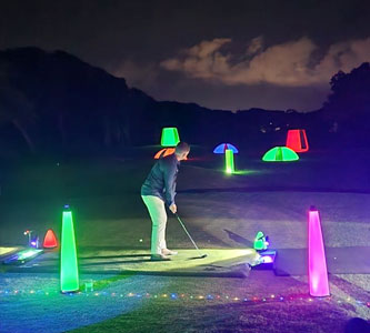 Golfer hitting a golf ball on a night golf driving range
